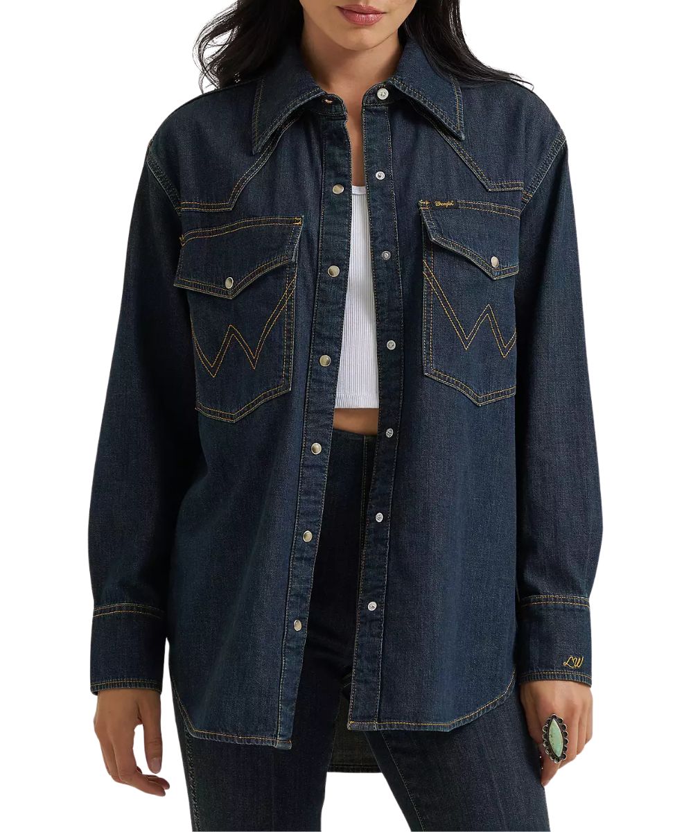 Front view of the women's Wrangler Lainey Wilson Boyfriend Dark Wash Denim Snap Shirt featuring the oversized chest pockets, western yokes, and pearl snaps