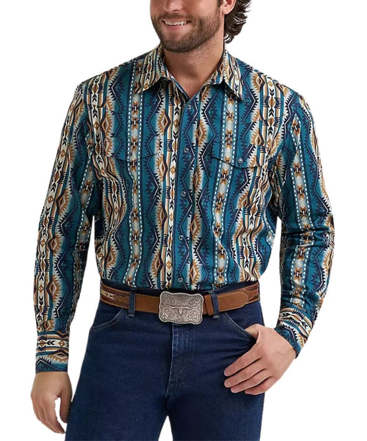 A man wearing a long-sleeve western-style button-up shirt with a blue, brown, and beige geometric pattern, paired with dark blue jeans and a brown belt with a silver buckle, against a plain white background.