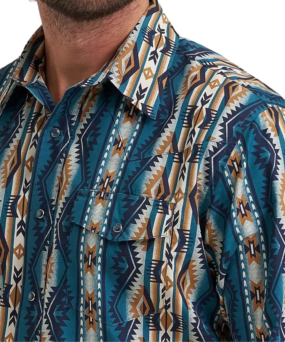 A close-up of a men's button-down shirt featuring a bold Southwestern geometric pattern in teal, navy, tan, and cream. The shirt is shown on a model, with the collar and upper chest visible against a plain white background.