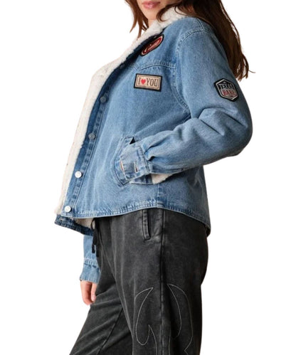 Side view of the women's medium wash denim jacket featuring the western-inspired patches throughout and button cuffs