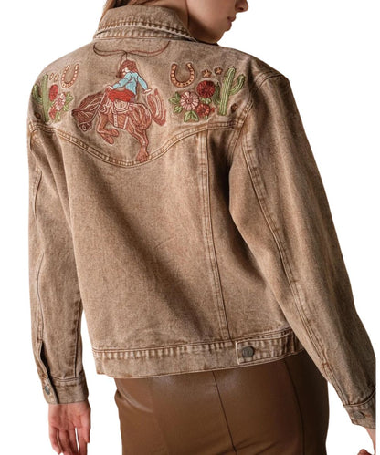 Back view of the women's mocha denim jacket featuring the curved back yoke with western embroidered motifs of a cowgirl, cacti, horseshoes, and floral accents