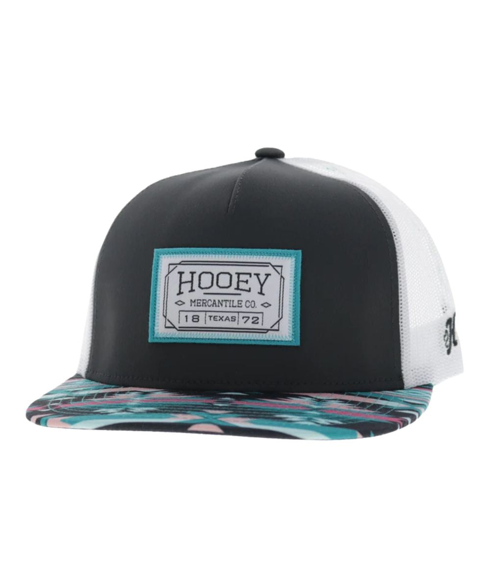 Left angled view of the unisex adult's Hooey Doc Trucker Cap featuring the charcoal front with a rectangle logo patch, the teal/charcoal/pink aztec hybrid bill, and white mesh sides 