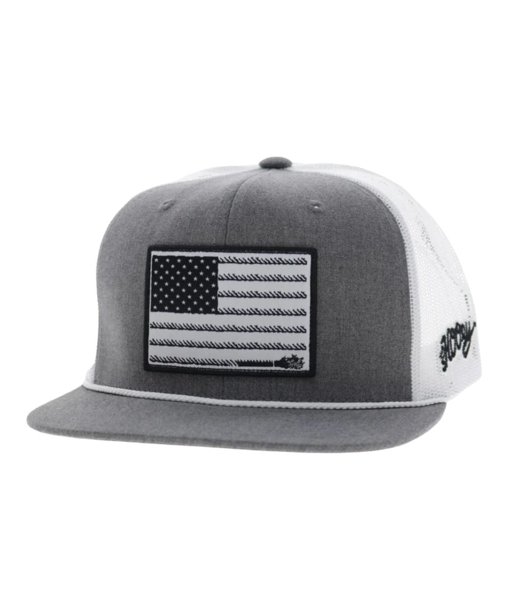 Left angled view of the unisex adult's Hooey Liberty Roper Trucker Cap featuring the grey front with a black/white American Flag liberty roper  rectangle patch, grey hybrid bill with a white brim rope, and white mesh sides