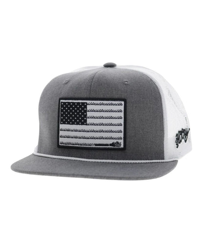 Left angled view of the unisex adult's Hooey Liberty Roper Trucker Cap featuring the grey front with a black/white American Flag liberty roper  rectangle patch, grey hybrid bill with a white brim rope, and white mesh sides