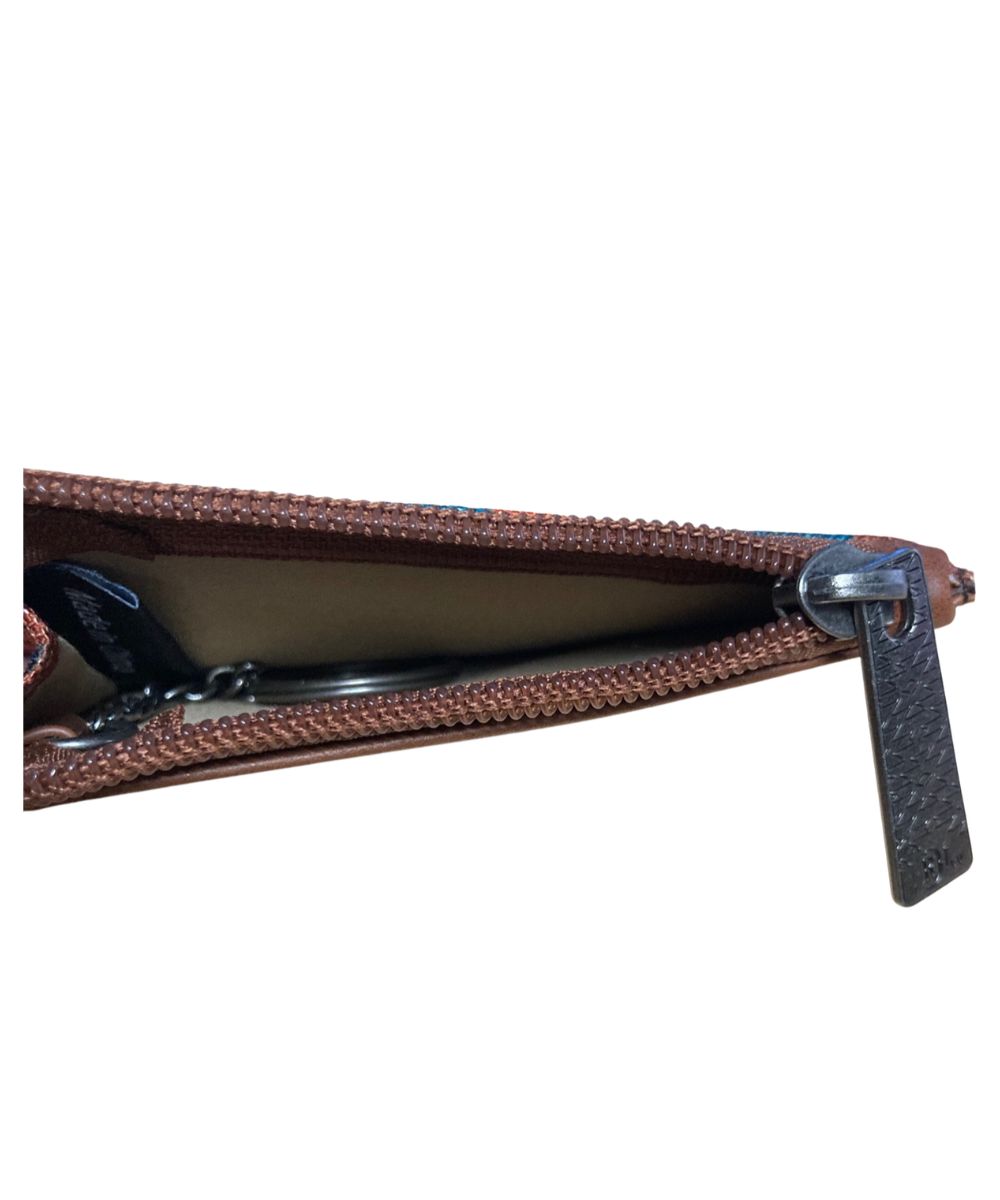 A close-up of a brown textured zippered pouch or wallet, showing the interior lining and a textured zipper pull tab against a plain white background.