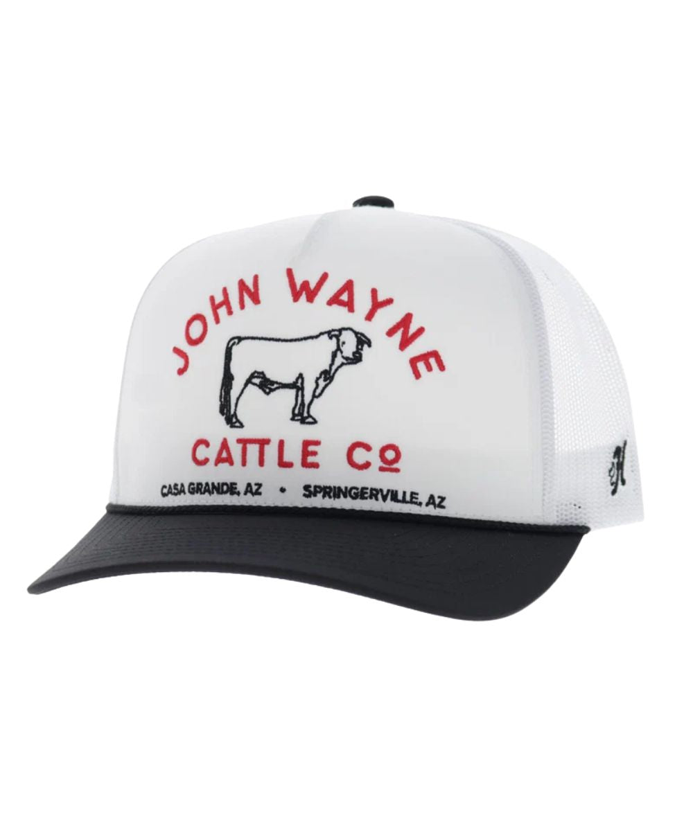 Left angled view of the unisex adult's Hooey John Wayne Cattle Co. Trucker Snapback Cap featuring the white front with black and red embroidery that reads: "John Wayne Cattle Co. - Casa Grande, AZ - Springerville, AZ" with a bull graphic, a black curved bill with a black brim rope, and white mesh sides