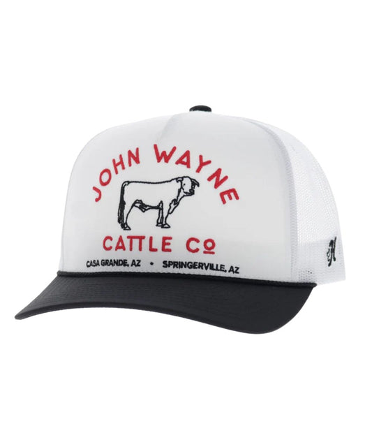 Left angled view of the unisex adult's Hooey John Wayne Cattle Co. Trucker Snapback Cap featuring the white front with black and red embroidery that reads: "John Wayne Cattle Co. - Casa Grande, AZ - Springerville, AZ" with a bull graphic, a black curved bill with a black brim rope, and white mesh sides