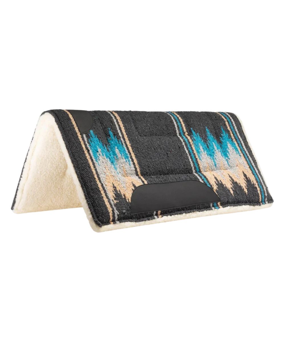 A folded saddle pad with a charcoal woven top featuring turquoise and beige geometric patterns, and a cream sherpa fleece lining, shown on a plain white background.