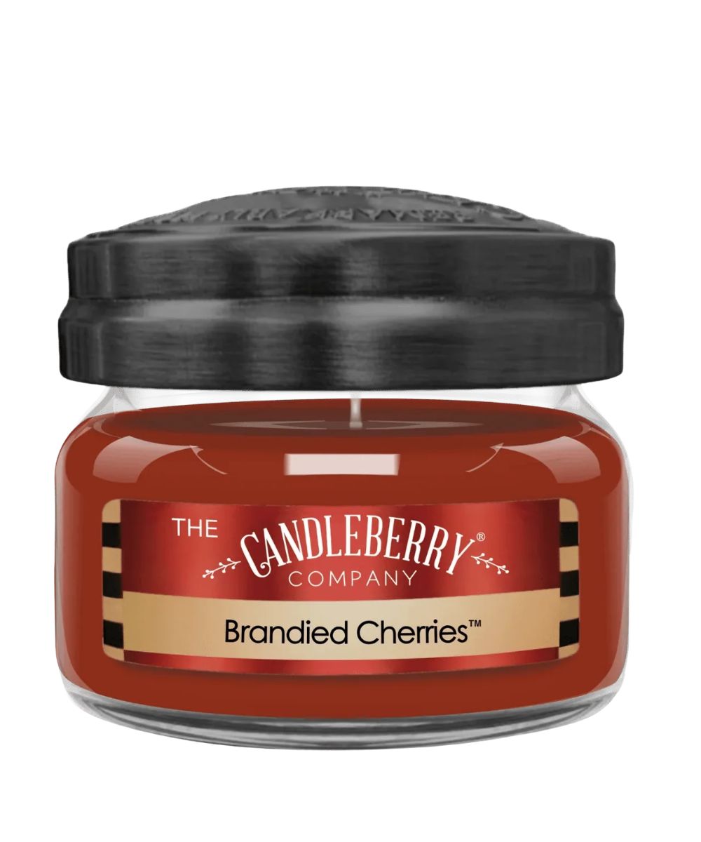 A jar candle from The Candleberry Company in the scent Brandied Cherries, featuring a glossy reddish-brown wax inside a clear glass jar with a black lid, set against a plain white background.