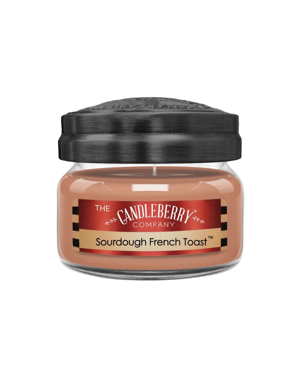A jar candle from The Candleberry Company in the Sourdough French Toast scent, featuring a warm peachy-brown wax inside a clear glass jar with a black lid and a red and gold label.