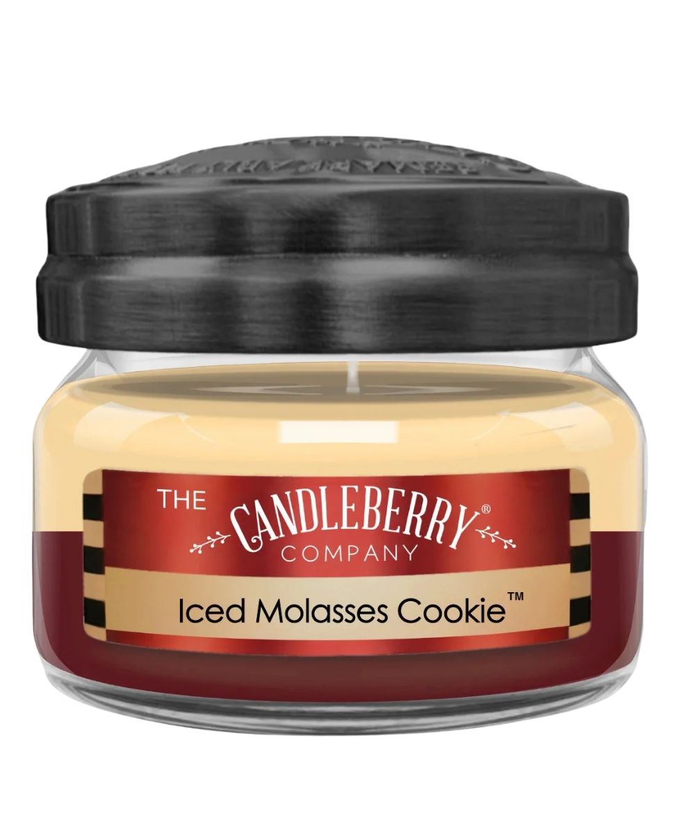 A jar candle from The Candleberry Company in the scent 'Iced Molasses Cookie'. The candle has a black lid, clear glass jar, and cream-colored wax with a red and beige label.