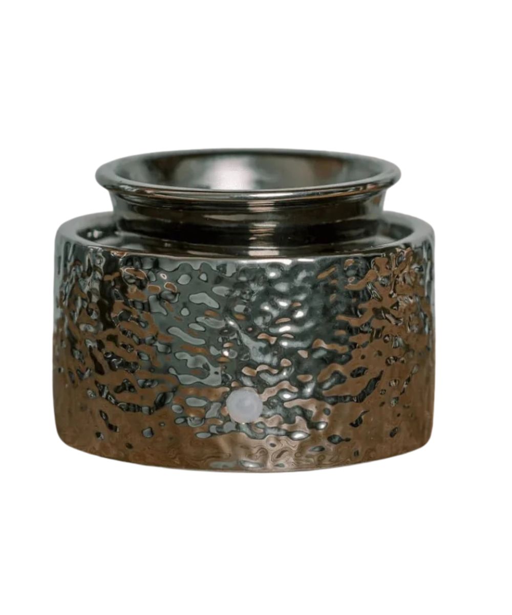 A hammered metal candle holder or vessel with a textured, metallic finish in silver and bronze tones, shown on a plain white background.