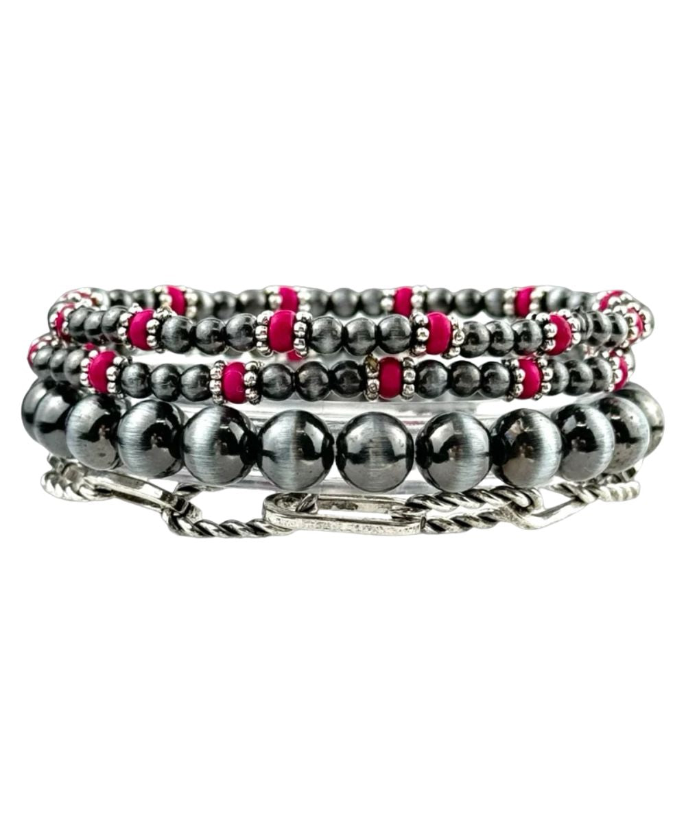A stack of four beaded and chain bracelets in black, silver, and hot pink, displayed on a clean white background.