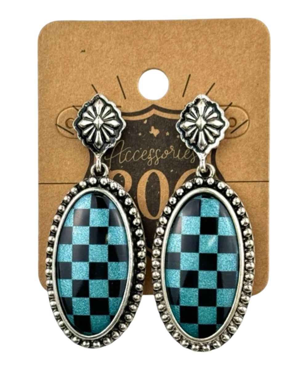 A pair of silver-tone dangle earrings with oval turquoise and black checkerboard-patterned centers, displayed on a brown kraft paper backing card.