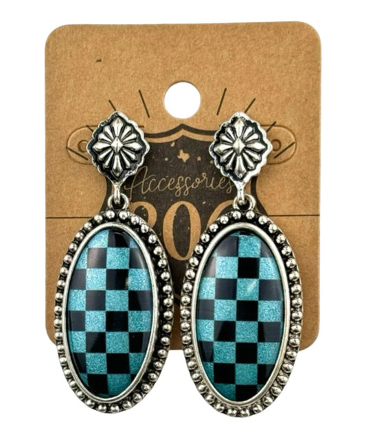 A pair of silver-tone dangle earrings with oval turquoise and black checkerboard-patterned centers, displayed on a brown kraft paper backing card.