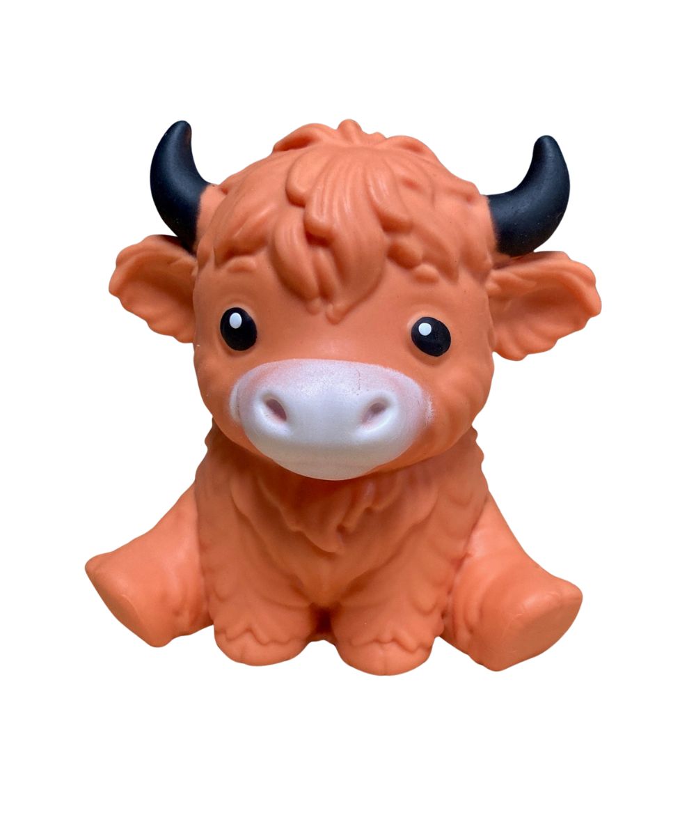 A small orange Highland cow squish with black horns, large black eyes, and a white snout, photographed against a plain white background.