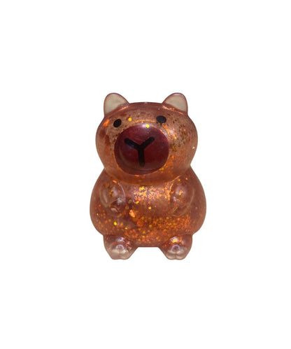 A small capybara glittery stress toy in a translucent amber-brown color, featuring a dark red nose and black eyes, set against a plain white background.