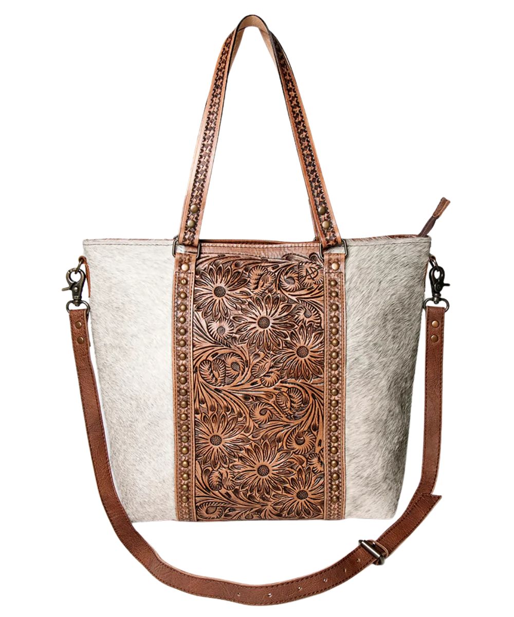 Hair-on cowhide women's tote bag featuring floral tooled details, a removable/adjustable crossbody strap, and top carry handles.