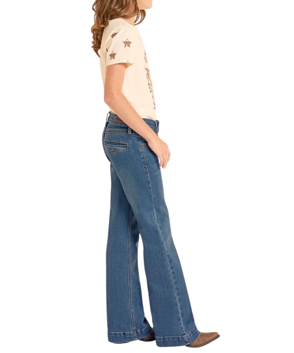 Side view of girl's jean in a medium wash featuring the trouser hem and light whiskering and sanding details.
