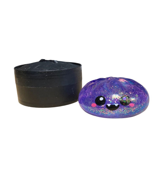 purple glitter squish toy with a fanged smile and dumpling storage case