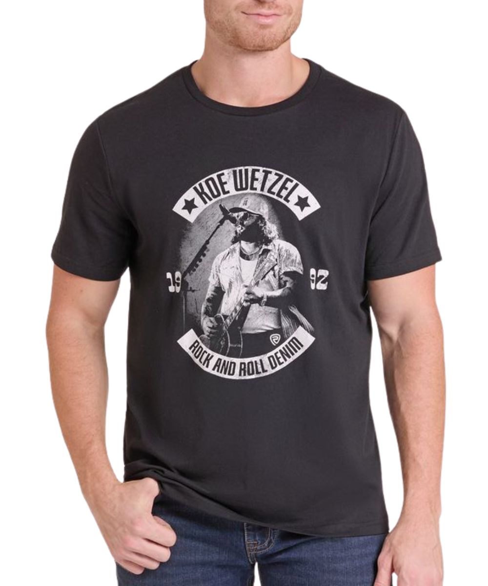 Front view of a man modeling the Rock & Roll Denim Koe Wetzel Black Tee featuring the front screen-printed Koe Wetzel singing and playing guitar graphic