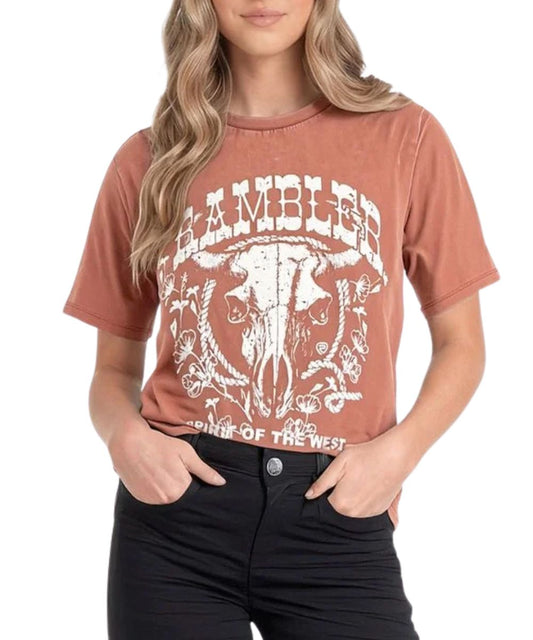 Front view of the women's rust Rock & Roll Cowgirl graphic tee featuring the short sleeves, crew neck, and a white screen-printed steer skull graphic that reads: "Rambler Spirit Of The West" with rope and floral decor