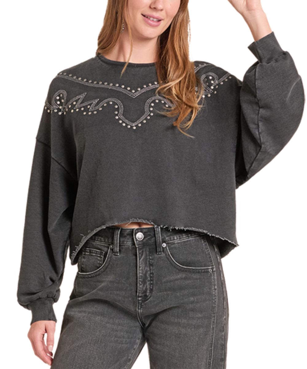 A woman wearing a dark gray cropped sweatshirt with western-style embroidery and stud detailing across the chest, paired with dark gray jeans, shown against a plain white background.
