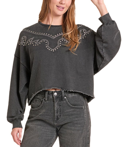 A woman wearing a dark gray cropped sweatshirt with western-style embroidery and stud detailing across the chest, paired with dark gray jeans, shown against a plain white background.