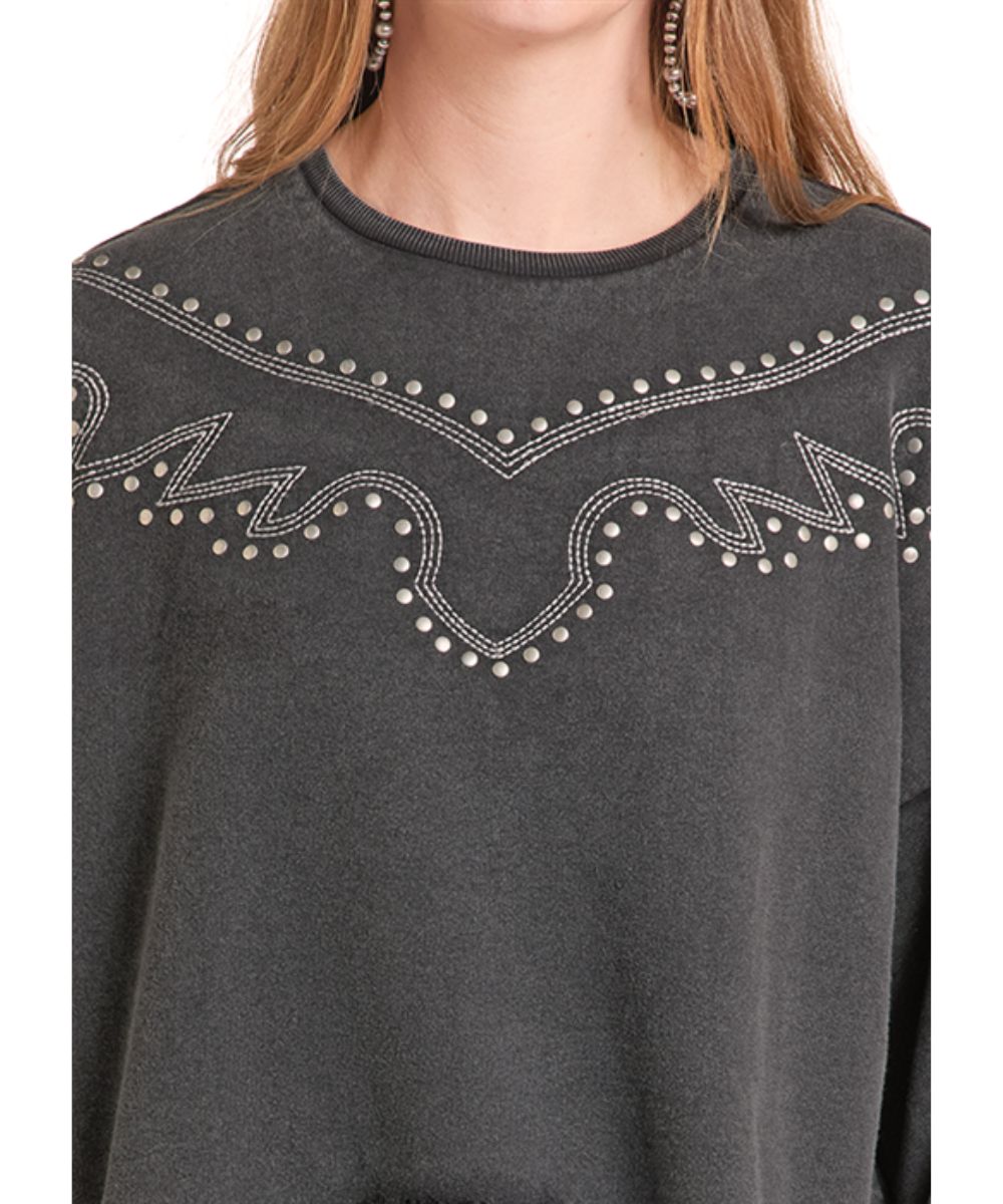 A close-up of a person wearing a dark charcoal gray crewneck sweatshirt with silver rhinestone western-style embroidery across the chest.