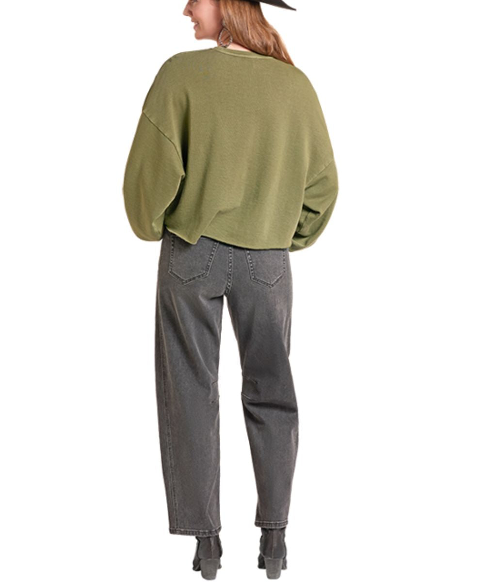A woman shown from the back wearing an olive green cropped knit sweater, dark gray jeans, and black boots against a plain white background.