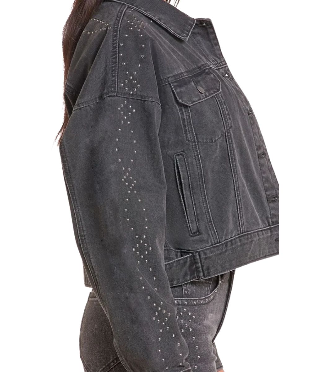 Side view of the women's black denim jacket featuring the welt hand pockets, spread collar, and studded sleeve details