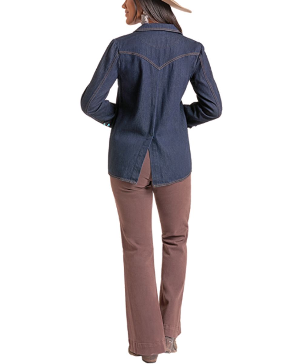 A woman shown from the back wearing a dark blue denim western-style shirt jacket with contrast stitching and brown pants, against a plain white background.