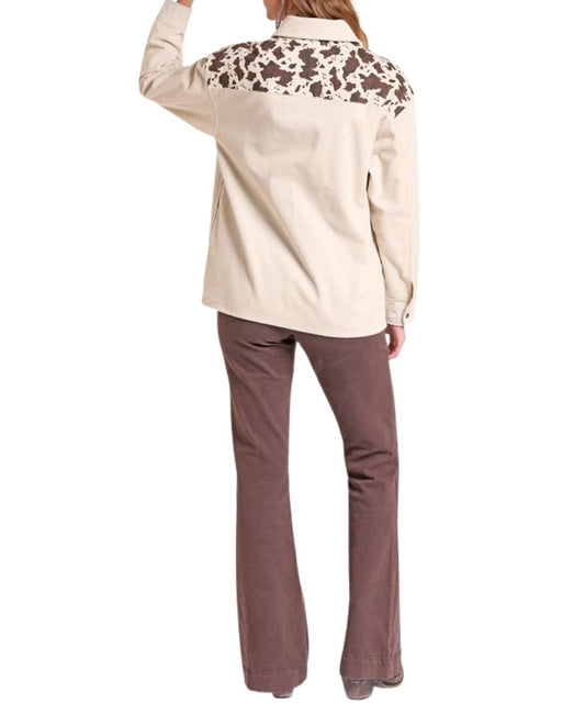 Back view of the women's long sleeve natural/beige colored corduroy shirt jacket featuring the straight back yoke with cow printed color blocked design
