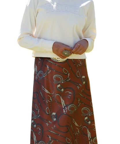 Close-up view of the women's burgundy satin skirt featuring the western tack-inspired print