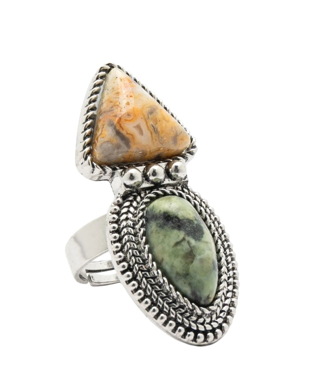 A silver-toned statement ring featuring a large triangular marbled stone in warm tan and brown tones above an oval green marbled stone, both set in ornate textured bezel settings on a white background.