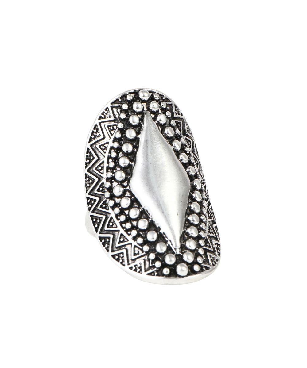 A silver-toned statement ring featuring a large central diamond-shaped inlay surrounded by textured bezel-set round stones, with a geometric patterned border, shown on a plain white background.