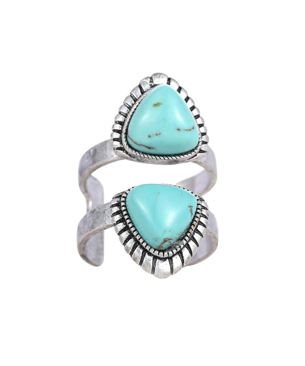 A silver-toned open wrap ring featuring two large, teardrop-shaped turquoise stones with natural matrix patterns, set in a textured, engraved sterling silver frame, shown against a plain white background.
