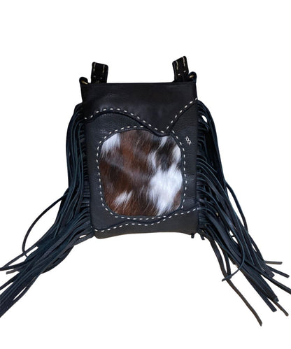 Front view of the women's black Pranee Cheyenne Darby Bag featuring the removable/adjustable crossbody strap, leather construction, hair-on-hide front center inlay, contrast buck stitching, side fringe, and a top zipper closure