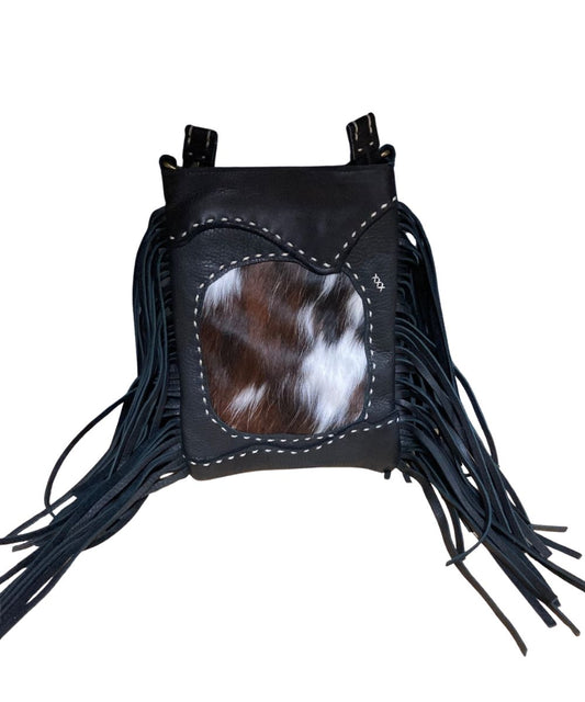 Front view of the women's black Pranee Cheyenne Darby Bag featuring the removable/adjustable crossbody strap, leather construction, hair-on-hide front center inlay, contrast buck stitching, side fringe, and a top zipper closure