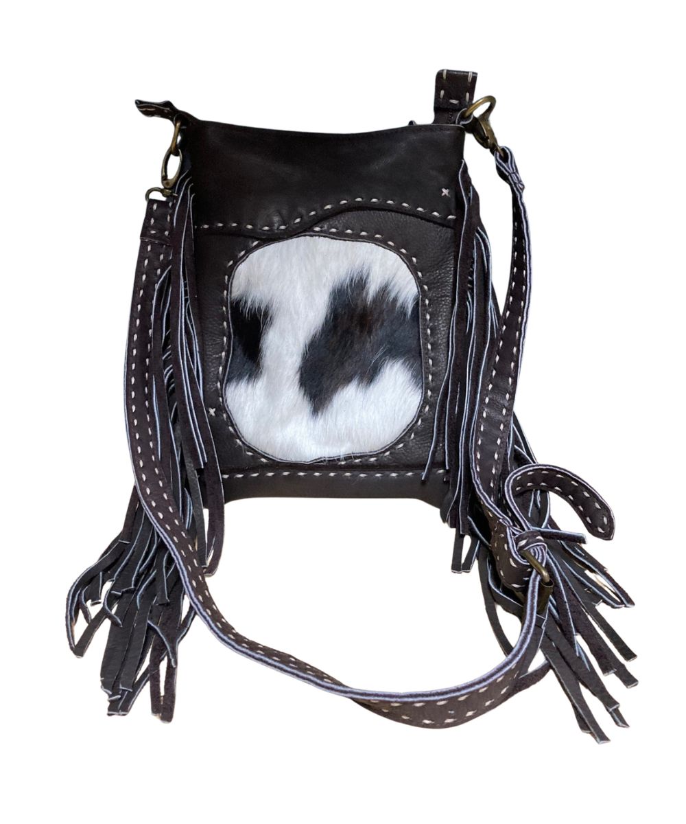 Front view of the women's brown Pranee Cheyenne Darby Bag featuring the removable/adjustable crossbody strap, leather construction, hair-on-hide front center inlay, contrast buck stitching, side fringe, and a top zipper closure