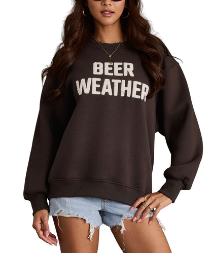 A woman wearing a charcoal crewneck sweatshirt with the words 'BEER WEATHER' printed in bold white letters across the chest, paired with light blue denim shorts.
