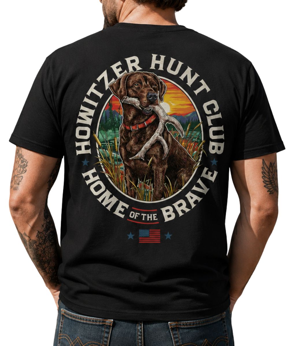 Back view of a man modeling the black tee featuring a screen print that reads: "Howitzer Hunt Club Home Of The Brave" with a hunting dog graphic