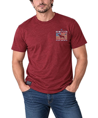 A man wearing a heathered red short-sleeve t-shirt with a 'Howitzer Patriot Hunting Co' graphic on the left chest, paired with blue jeans, against a plain white background.