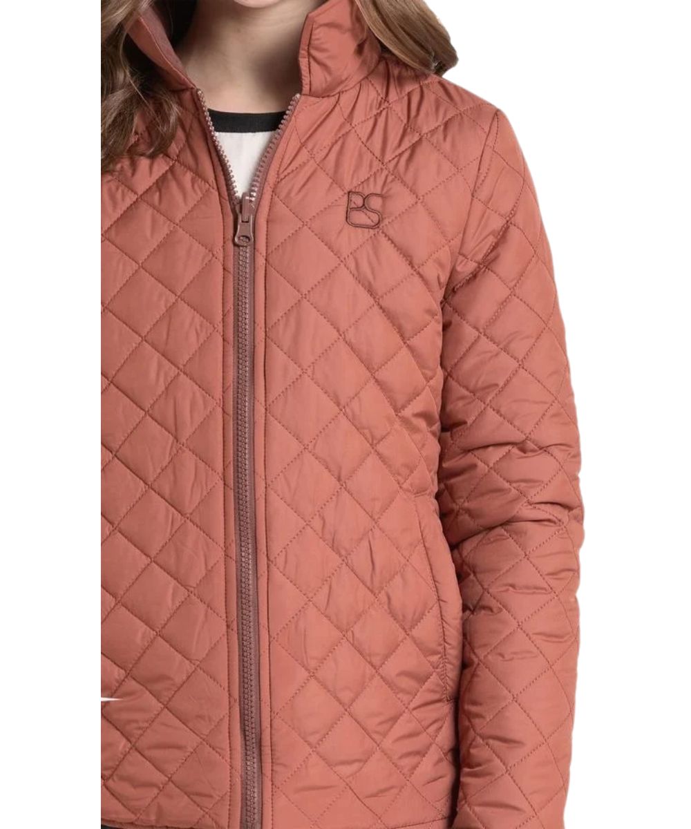 Close-up view of the girl's camel quilted reversible jacket featuring the logo embroidery at the left chest. This camel jacket reverses to brown