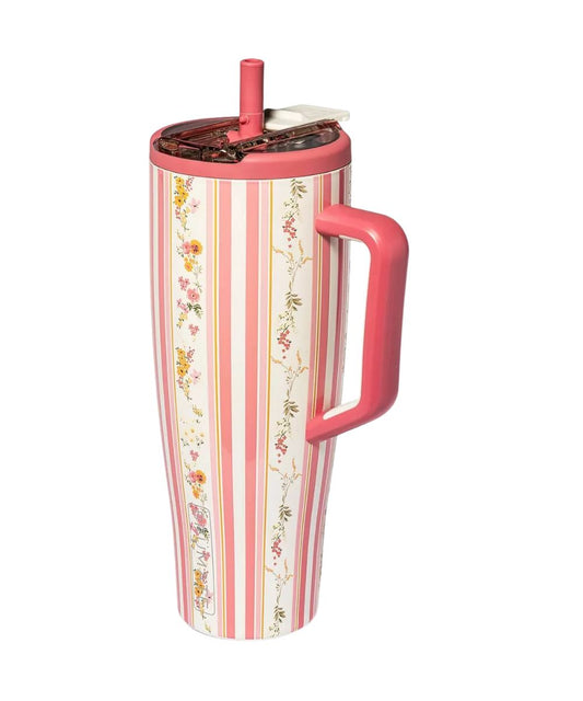 A tall travel tumbler with a pink handle and lid, featuring a vertical pink and cream stripe pattern with delicate floral illustrations, shown on a white background.