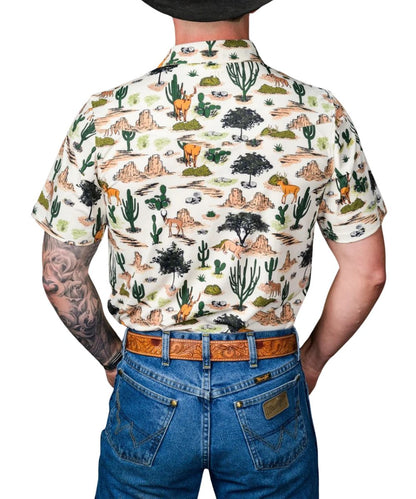 Back view of the men's white short sleeve pearl snap polo shirt featuring the single point back yoke, brown geometric desert wilderness print, and 4-way stretch fabric