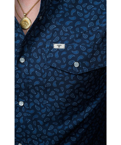 Close-up view of the men's navy pearl snap shirt featuring the single point snap flap chest pockets with a pen/sunglasses slot and the blue paisley print