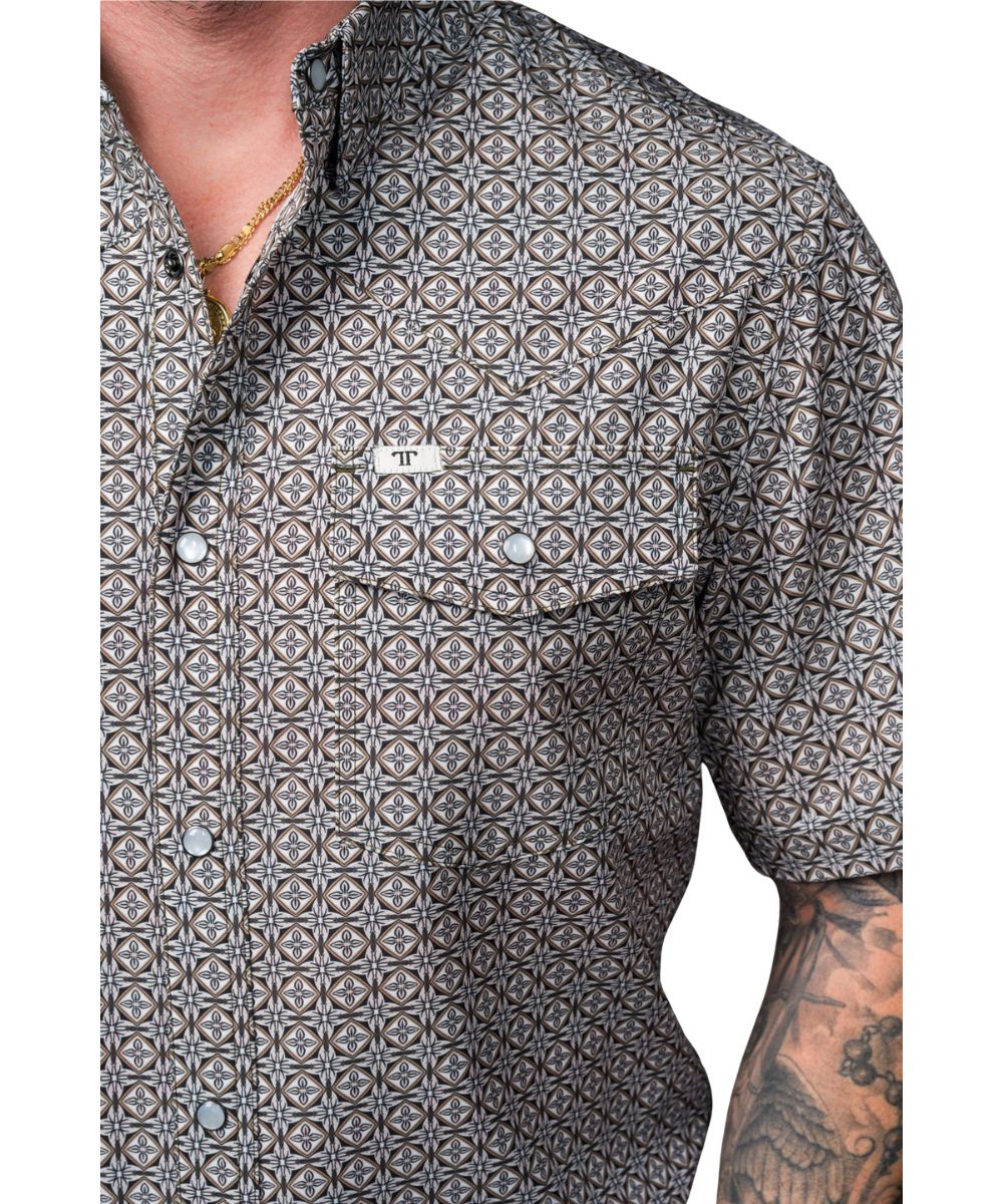 Close-up view of the geometric print, pearl snaps, hidden snap-down collar, chest pockets with a pen/sunglasses slot, on the men's lightweight and breathable snap shirt