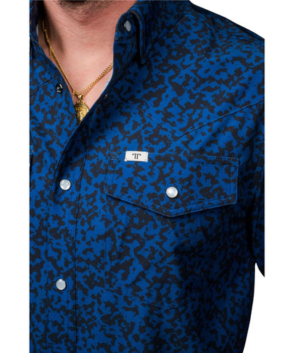 Close-up view of the black geometric print on the men's royal blue pearl snap shirt featuring the snap flap chest pockets with a hidden pen/sunglasses slot and logo label at the left chest pocket