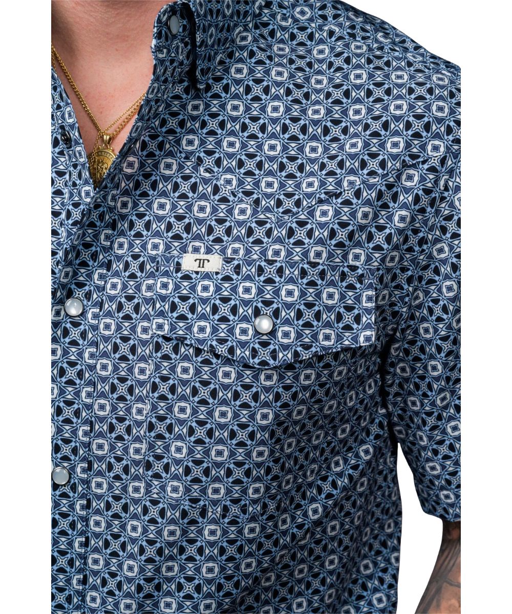 Close-up view of the geometric print, western yokes, and snap flap chest pocket featuring the pen/sunglasses slot and logo label at the left chest pocket